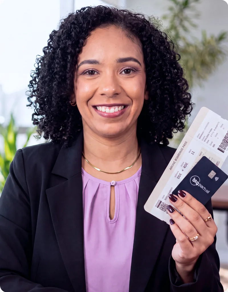 Aline Lucas segurando cartão e passagens após aprender a viajar com milhas aéreas.