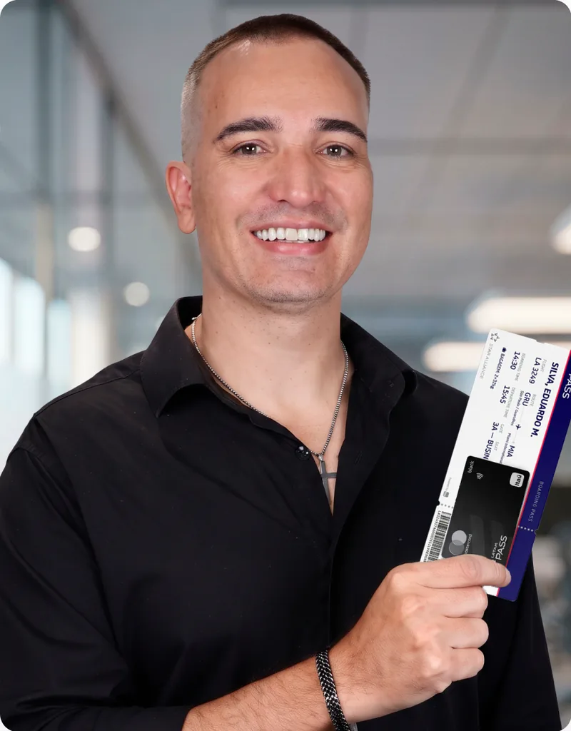 Eduardo Alves segurando cartão e passagens após aprender como acumular milhas.