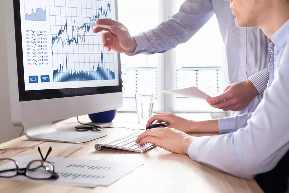 Traders with forex trading charts and graphs on computer screen