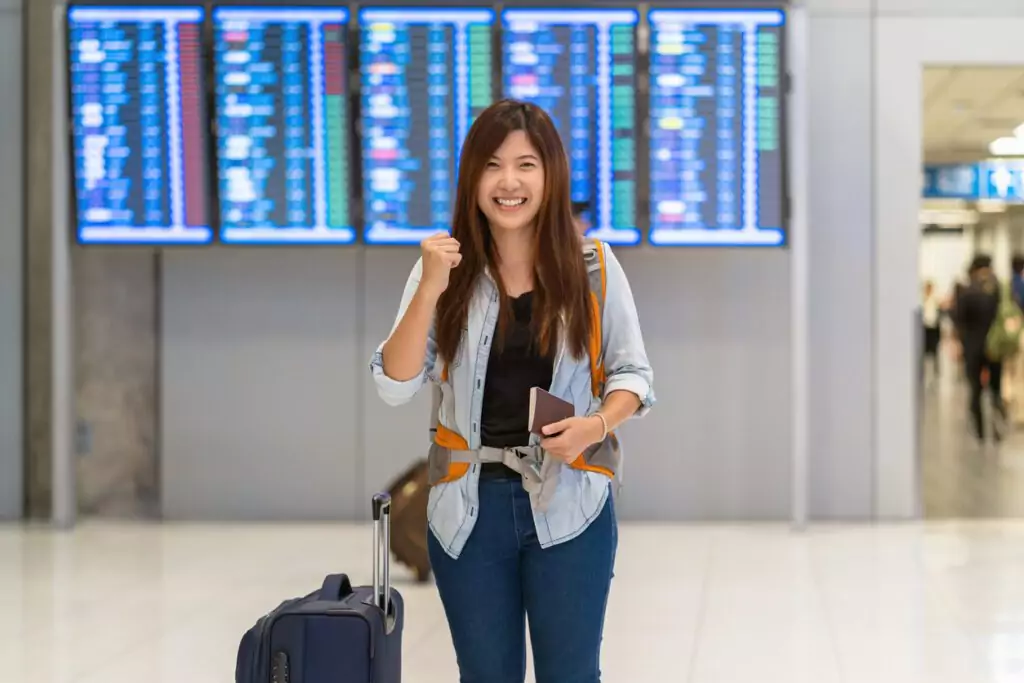 Viajante asiático com bagagem com passaporte andando no aeroporto atenta as regras de tursimo e viagens aéreas em 2022.